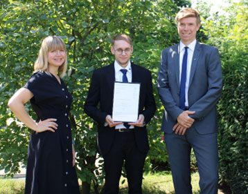 Nina Holena und André Bade mit Philip Eichhorn und seinem Abschlusszeugnis